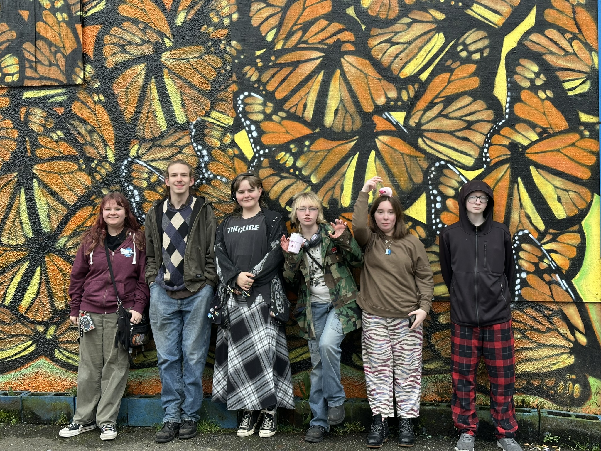 A group of Cedar students standing in front of a vivid butterfly mural